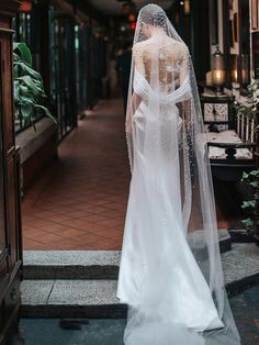 the back of a bride's wedding dress in front of a doorway with potted plants