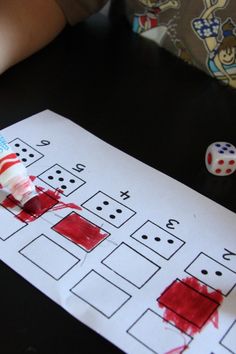 a child's hand holding a toothbrush over a piece of paper with dices on it