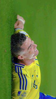 a man leaning against a green wall with his arm in the air