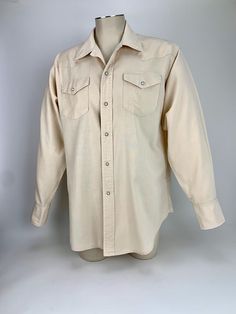 1960's Western Cowboy Shirt in a pale fleshy beige color.. The fabric is 100% cotton in a medium weight fabric.  This cowboy shirt has small metal snap buttons that are set with variegated white marble.,  There is a western style yoke and button down flap patch pockets with snaps & shirt tails. There are 3 metal snaps as closures on each cuff. The original maker label is missing, just the smaller label that says: STRETCH There is size label that reads: X-L This is in GOOD  VINTAGE CONDITION. with some general wear.. &  a few snag holes.. see last couple images for arrows pointing out these areas. To be certain of the size, check the measurements below: Measurements: ( lying flat) From the top of the shoulder seam to shoulder seam: 20-1/2 inches Chest taken from under the armpit to armpit: Cowboy Button Up Shirt, 1960s Mens Fashion, Vintage Cowboy Shirts, Western-themed Cotton Shirt With Button Closure, Western Snap Button-up Tops, Western Snap Button-up Shirt, Cowboys Shirt, Mens Oxfords, Cow Boy