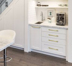 a kitchen with white cabinets and marble counter tops, along with an espresso machine