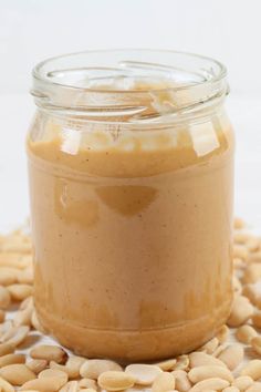 a jar filled with peanut butter sitting on top of a pile of peanuts