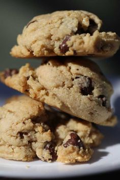 three chocolate chip cookies stacked on top of each other in front of a white plate