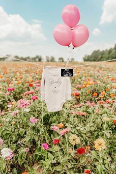 two pink balloons are tied to a string in the middle of a field full of flowers