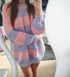 a woman taking a selfie in front of a mirror wearing a pink and purple sweater