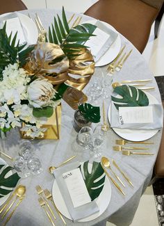 the table is set with white and gold plates, silver napkins, and flowers