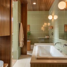 a bathroom with green tile and wood accents