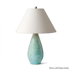 a lamp with a white shade on it and a blue vase sitting next to it