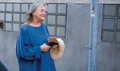 an older woman walking down the street with a hat on