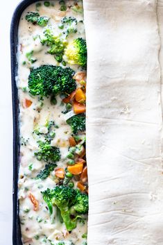 a casserole dish with broccoli, carrots and cheese in it