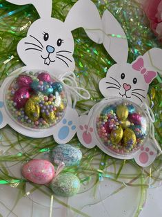 three plastic easter eggs with bunny ears on them and some candy in the bowl next to each other