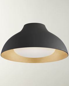 a black and gold colored light fixture on a white wall in an empty room with no one around it