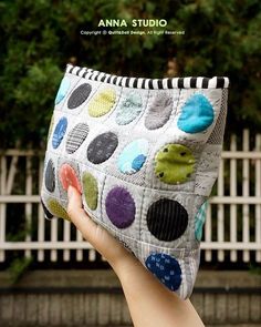 a hand holding up a polka dot purse