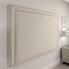 a white headboard with beaded trim on the wall next to a couch and lamp