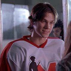 a young man in a hockey jersey standing next to a woman