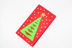 a red and green christmas card on a white surface with gold dots around the tree