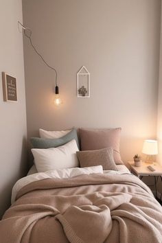 a bed with blankets and pillows on top of it in a bedroom next to a lamp