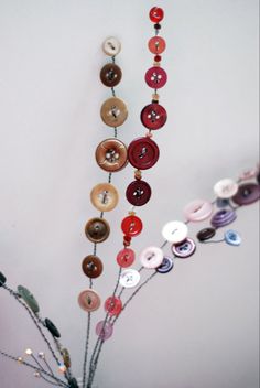 a vase filled with lots of different colored buttons hanging from it's sides,