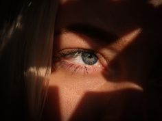 a woman's blue eyes are seen through the shadow of her head and hand