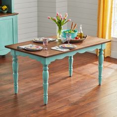 a wooden table with two plates on it and flowers in vases at the top