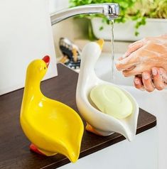 someone is washing their hands in the sink with soap and rubber ducky toys next to them