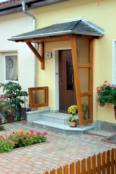 a small yellow house with potted plants and flowers