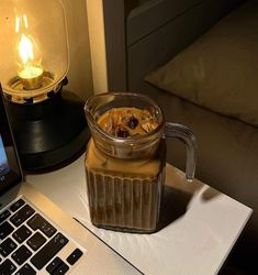 a jar of liquid sitting on top of a table next to a laptop computer and lamp