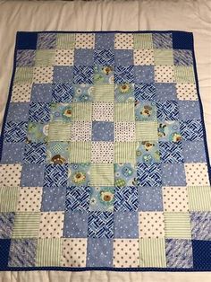 a blue and green quilt on top of a bed