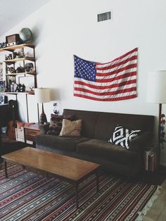 a living room with a couch, coffee table and american flag hanging on the wall