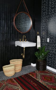 the bathroom is decorated with black and white wallpaper, gold faucet, bamboo basket