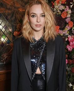 a model poses for the camera in front of flowers and greenery at an event