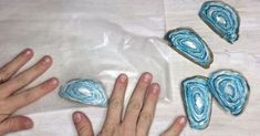 two hands reaching for some blue cookies on a table