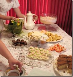 a table topped with lots of desserts and pastries next to a vase filled with flowers