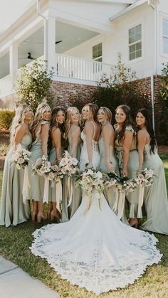 a group of women standing next to each other in front of a white house with flowers