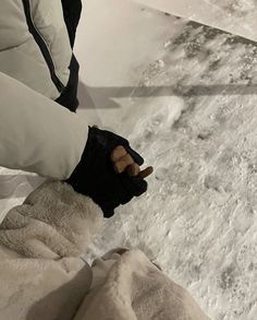 a person in white jacket and black gloves standing on snow covered ground