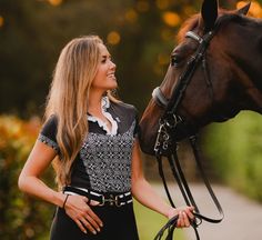 a woman standing next to a brown horse