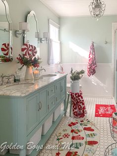 a bathroom decorated for christmas with red and white decorations on the vanity, rugs and towels