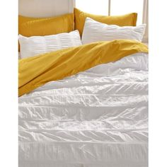 an unmade bed with yellow and white sheets