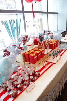 a long table with candy and candies on it in front of a large window