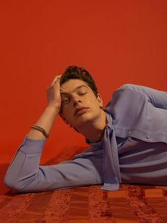 a woman laying on the floor with her head in her hands and eyes closed, wearing a blue shirt