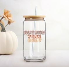 a glass with a straw in it sitting next to a pumpkin and some other items