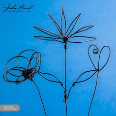 three metal flowers with hearts on them against a blue background, the stems are shaped like leaves