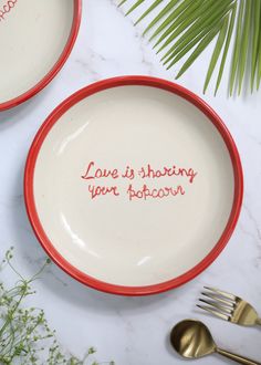 two red and white plates with the words love is sharing your popcorn written on them