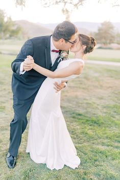 a bride and groom kissing in the grass