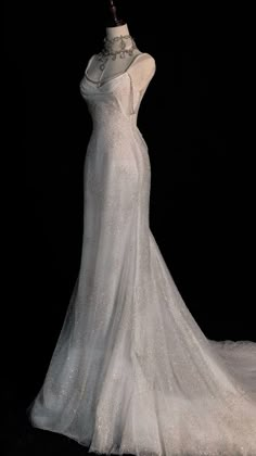 a white wedding dress on display in front of a black background with the back of it's neckline