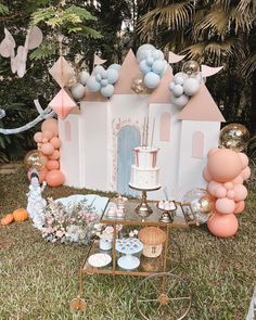 a cake and balloons set up on the lawn for a princess birthday party with castle decorations