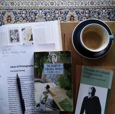 there is a cup of coffee and some books on the table next to each other