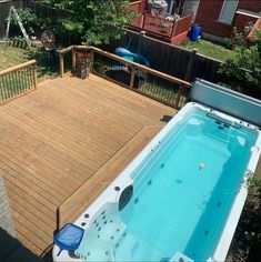 a hot tub sitting on top of a wooden deck next to a fenced in yard