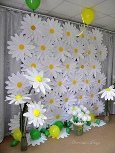 white daisies and balloons are on display in front of a backdrop