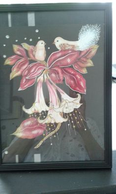 a painting with birds and flowers on it in a black framed frame next to a window